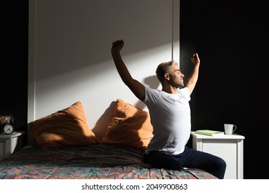 Hispanic Man Stretching Out In His Bedroom. Morning Routine Concept