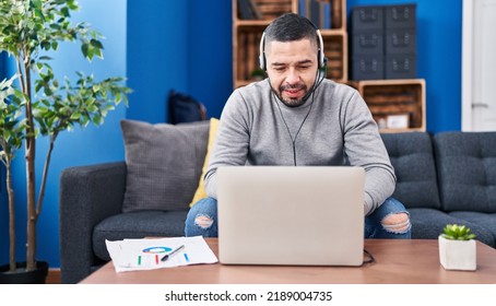 Hispanic man using laptop working from home looking positive and happy standing and smiling with a confident smile showing teeth  - Powered by Shutterstock