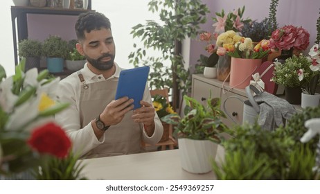 Hispanic man using tablet among vibrant flowers indoors in a flower shop. - Powered by Shutterstock