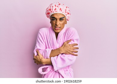 Hispanic Man Wearing Make Up Wearing Shower Towel Cap And Bathrobe Shaking And Freezing For Winter Cold With Sad And Shock Expression On Face 