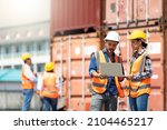 Hispanic Man worker and woman Supervisor checking and control loading Containers box by laptop computer at container yard port of import and export goods. Unity and teamwork concept