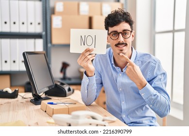 Hispanic Man Working At Small Business Ecommerce Holding No Banner Smiling Happy Pointing With Hand And Finger 