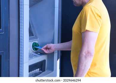 Hispanic Mature Adult Man Entering The Credit Card In The ATM Of A Bank.