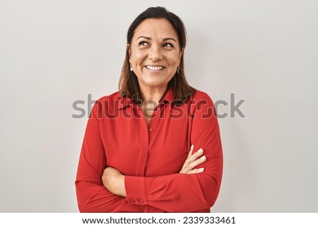 Hispanic mature woman standing over white background smiling looking to the side and staring away thinking. 