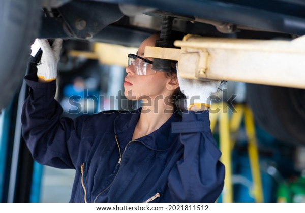 hispanic  mechanic woman working under\
vehicle in a car service. Empowering working woman\

