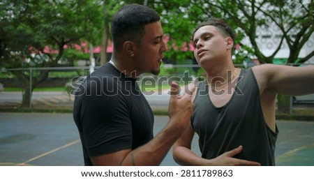 Hispanic men arguing face to face on outdoor basketball court, pointing fingers and gesturing emotionally as tension rises, camera circling around escalating street confrontation