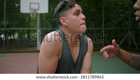 Hispanic men arguing face to face on outdoor basketball court, pointing fingers and gesturing emotionally as tension rises, camera circling around escalating street confrontation