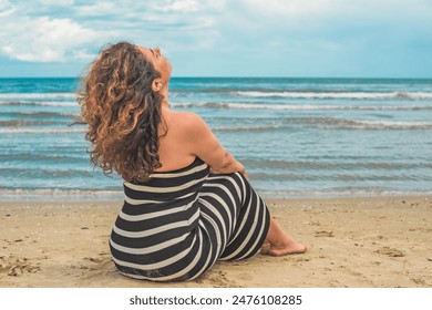 Hispanic middle age woman with a curly hair relaxing on a beach. Natural women's beauty, feminine concept - Powered by Shutterstock