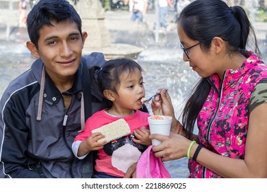 Hispanic Mom And Dad Feeding Their Little Daughter. Mexican Family