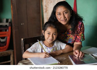 Hispanic mom helping her little daughter do her homework - Mom teaching her daughter to read and write at home - Mayan family at home - Shutterstock ID 2123280770