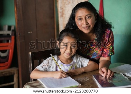 Hispanic mom helping her little daughter do her homework - Mom teaching her daughter to read and write at home - Mayan family at home Stock foto © 