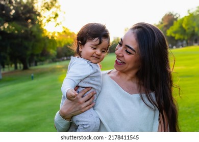 Hispanic Mom And Son Hugging Outdoors In A Beautiful Green Field