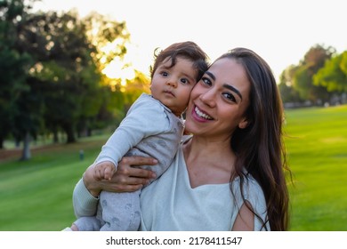 Hispanic Mom And Son Hugging Outdoors In A Beautiful Green Field