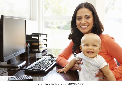 Hispanic mother with baby in working home office