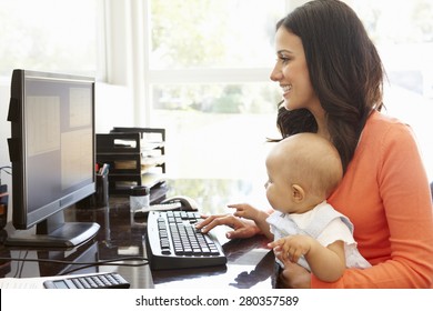 Hispanic mother with baby working in home office