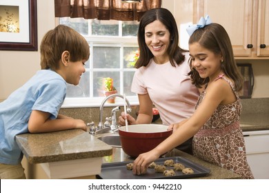 Hispanic Mother And Children In Kitchen Making Cookies.