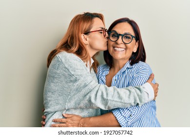 Hispanische Mutter und Tochter lächeln glücklich. Steht mit Lächeln auf Gesicht Umarmung und Küssen auf isoliertem weißem Hintergrund.