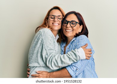 Hispanic Mother And Daughter Smiling Happy And Hugging Standing Over Isolated White Background.