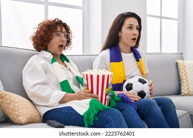 Hispanic Mother And Daughter Watching Football Supporting Team Scared And Amazed With Open Mouth For Surprise, Disbelief Face 