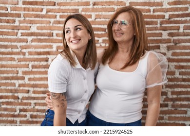 Hispanic Mother And Daughter Wearing Casual White T Shirt Looking Away To Side With Smile On Face, Natural Expression. Laughing Confident. 