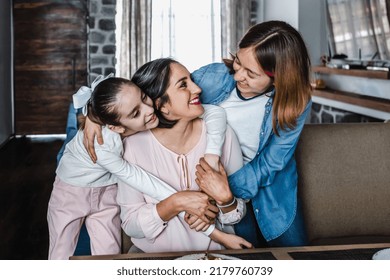 Hispanic Mother Hugging Her Daughters At Cozy Living Room At Home In Mexico Latin America. Family Time