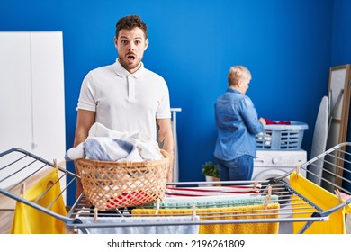 Hispanic Mother And Son Hanging Clothes At Clothesline Scared And Amazed With Open Mouth For Surprise, Disbelief Face 