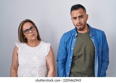 Hispanic Mother And Son Standing Together In Shock Face, Looking Skeptical And Sarcastic, Surprised With Open Mouth 