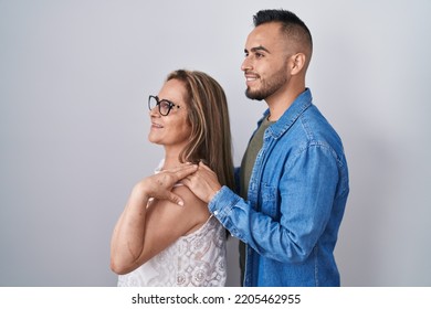 Hispanic Mother And Son Standing Together Looking To Side, Relax Profile Pose With Natural Face And Confident Smile. 