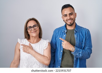 Hispanic Mother And Son Standing Together Cheerful With A Smile On Face Pointing With Hand And Finger Up To The Side With Happy And Natural Expression 