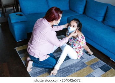 Hispanic Mother Wearing Face Mask On Her Daughter With Cerebral Palsy At Home In Latin America In Disability Concept During Covid Coronavirus Pandemic