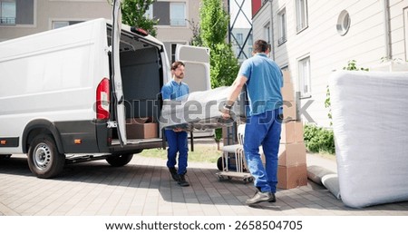 Hispanic Movers In Blue Uniform Loading Truck For Furniture Delivery