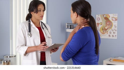 Hispanic OBGYN talking to african american patient with tablet