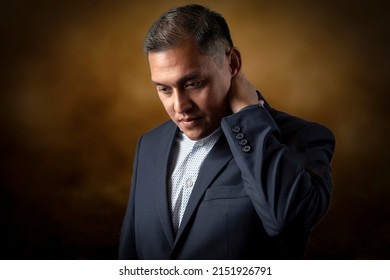 Hispanic Or Pacific Islander Man In Business Suit With Serious Look Against A Brown Background 