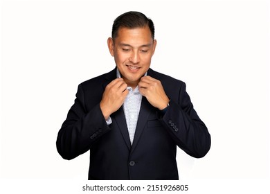 Hispanic Or Pacific Islander Man In Business Suit Smiling While Adjusting His Collar And Not Looking At The Camera Shot On A White Background