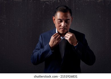 Hispanic or pacific islander man looking down and adjusting his collar  - Shutterstock ID 2151926831