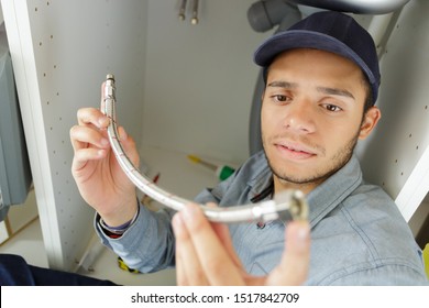 Hispanic Plumber Working Under Sink