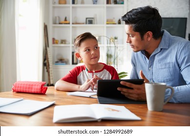 Hispanic Pre-teen Boy Sitting At Dining Room Table Working With His Home School Tutor