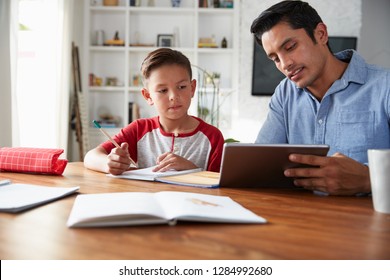 Hispanic Pre-teen Boy Sitting At Table Working With His Home School Tutor, Using Tablet Computer