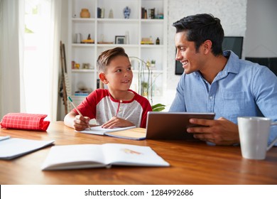 Hispanic Pre-teen Boy Sitting At Table Working With His Home School Tutor, Smiling At Each Other