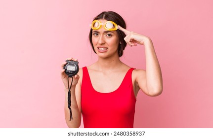hispanic pretty woman feeling confused and puzzled, showing you are insane. swimmer and timer concept - Powered by Shutterstock