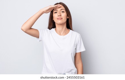 hispanic pretty woman greeting the camera with a military salute in an act of honor and patriotism, showing respect - Powered by Shutterstock