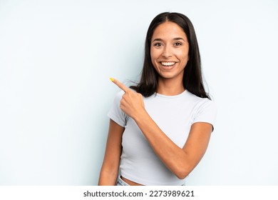 hispanic pretty woman looking excited and surprised pointing to the side and upwards to copy space - Shutterstock ID 2273989621