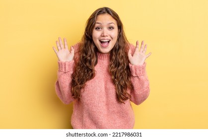 Hispanic Pretty Woman Looking Happy And Excited, Shocked With An Unexpected Surprise With Both Hands Open Next To Face