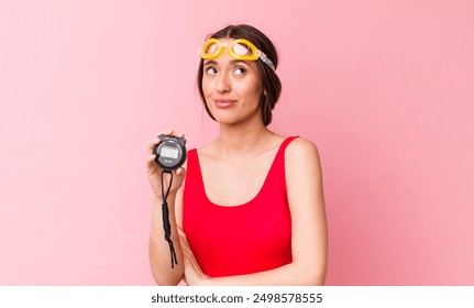 hispanic pretty woman shrugging, feeling confused and uncertain. swimmer and timer concept - Powered by Shutterstock