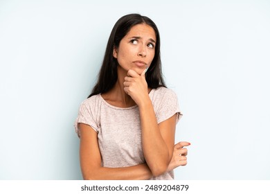 hispanic pretty woman thinking, feeling doubtful and confused, with different options, wondering which decision to make - Powered by Shutterstock