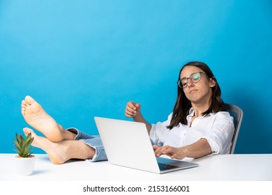 Hispanic Pretty Woman Working On Laptop Feet On Desk Isolated On Blue Background.