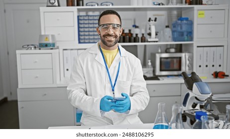 Hispanic scientist man with beard smiling in laboratory wearing lab coat and safety glasses, holding smartphone. - Powered by Shutterstock