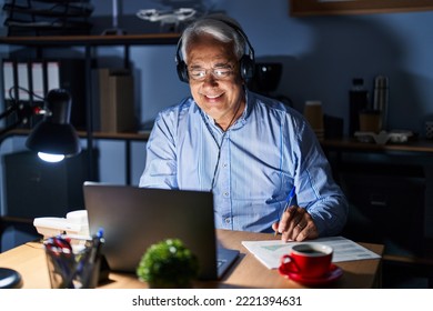 Hispanic Senior Man Wearing Call Center Agent Headset At Night With A Happy And Cool Smile On Face. Lucky Person. 