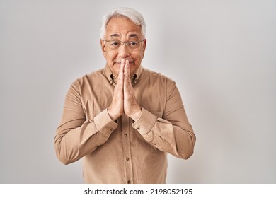 Hispanic Senior Man Wearing Glasses Praying With Hands Together Asking For Forgiveness Smiling Confident. 