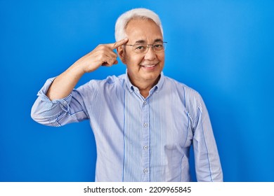 Hispanic Senior Man Wearing Glasses Smiling Pointing To Head With One Finger, Great Idea Or Thought, Good Memory 